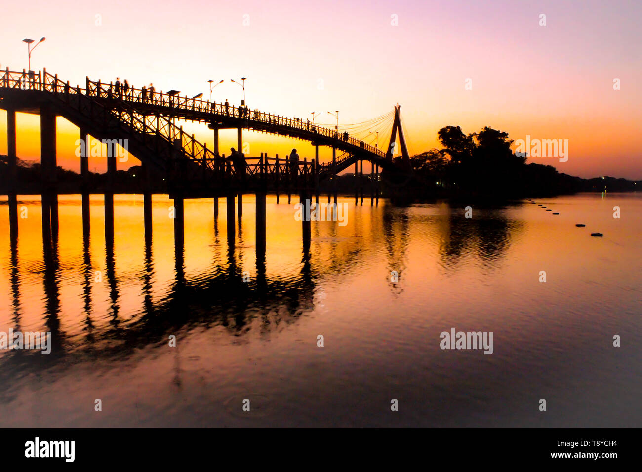 Persone sagome guardando colorato tramonto tramonto a ponte Ponte sul fiume persone ammirare Silhouette Silhouette di sfondo delle persone che camminano attraverso la ico Foto Stock