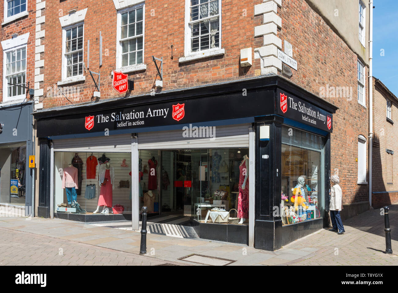 Donna che guarda nella finestra dell'Esercito della salvezza la carità shop su un elevato angolo di strada in Worcestershire città mercato di Evesham Foto Stock
