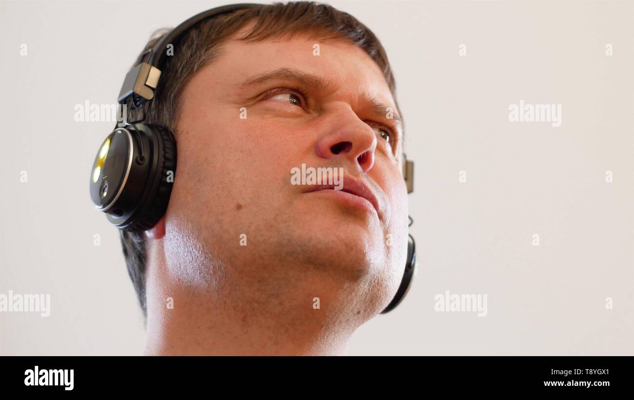 Millenial giovane uomo che indossa senza fili cuffie nero rock per la musica e il sorriso di cantare insieme, su uno sfondo bianco. Le persone di mezza età caucasian m Foto Stock