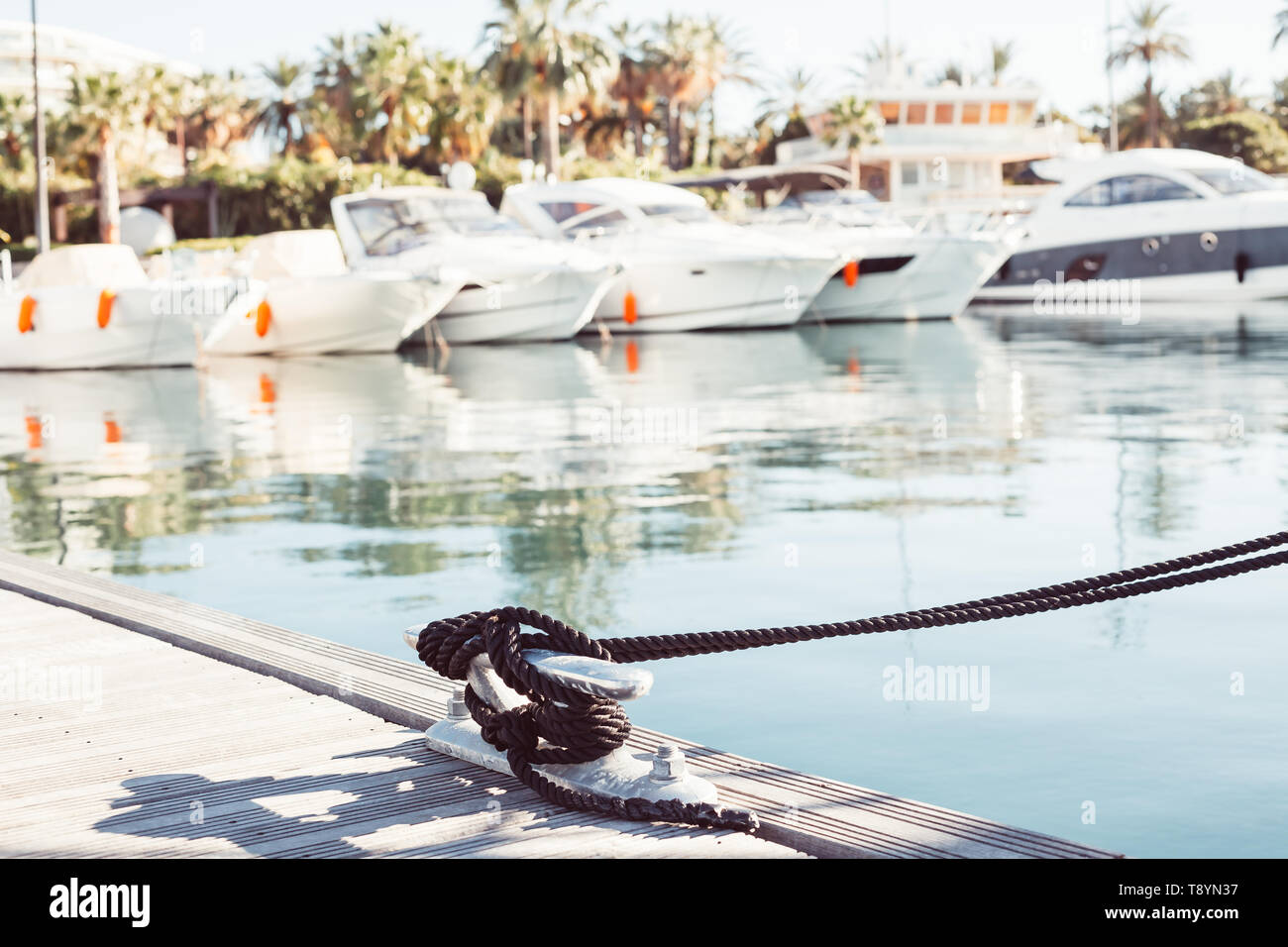 Ormeggio yacht corda con una estremità annodata legato attorno un gancio su un molo in legno contro vista marina Foto Stock