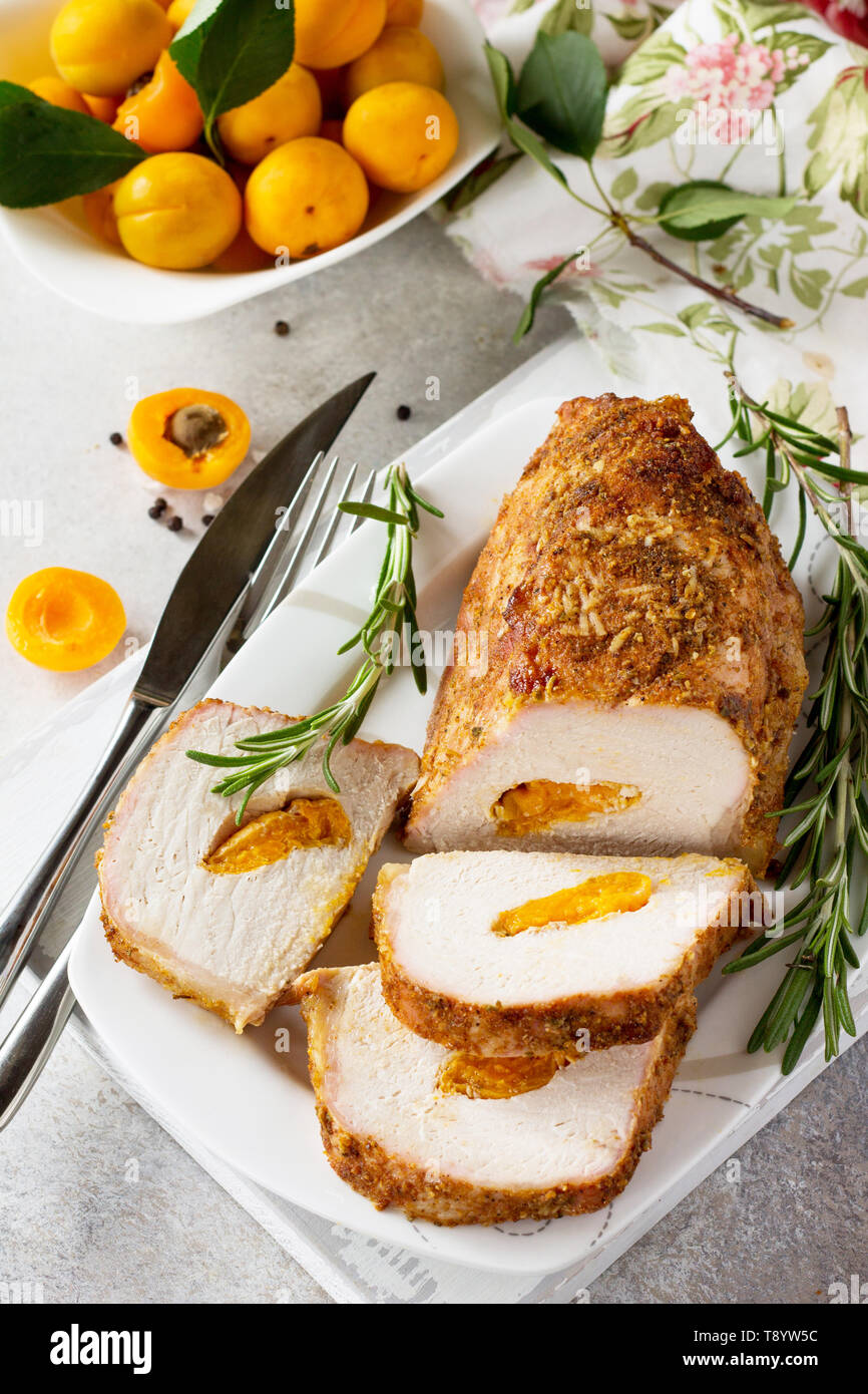 Rotolo di carne (involtino) con ripieno di albicocca e spezie su una luce di pietra o di sfondo di ardesia. La Giornata del ringraziamento antipasto. Foto Stock