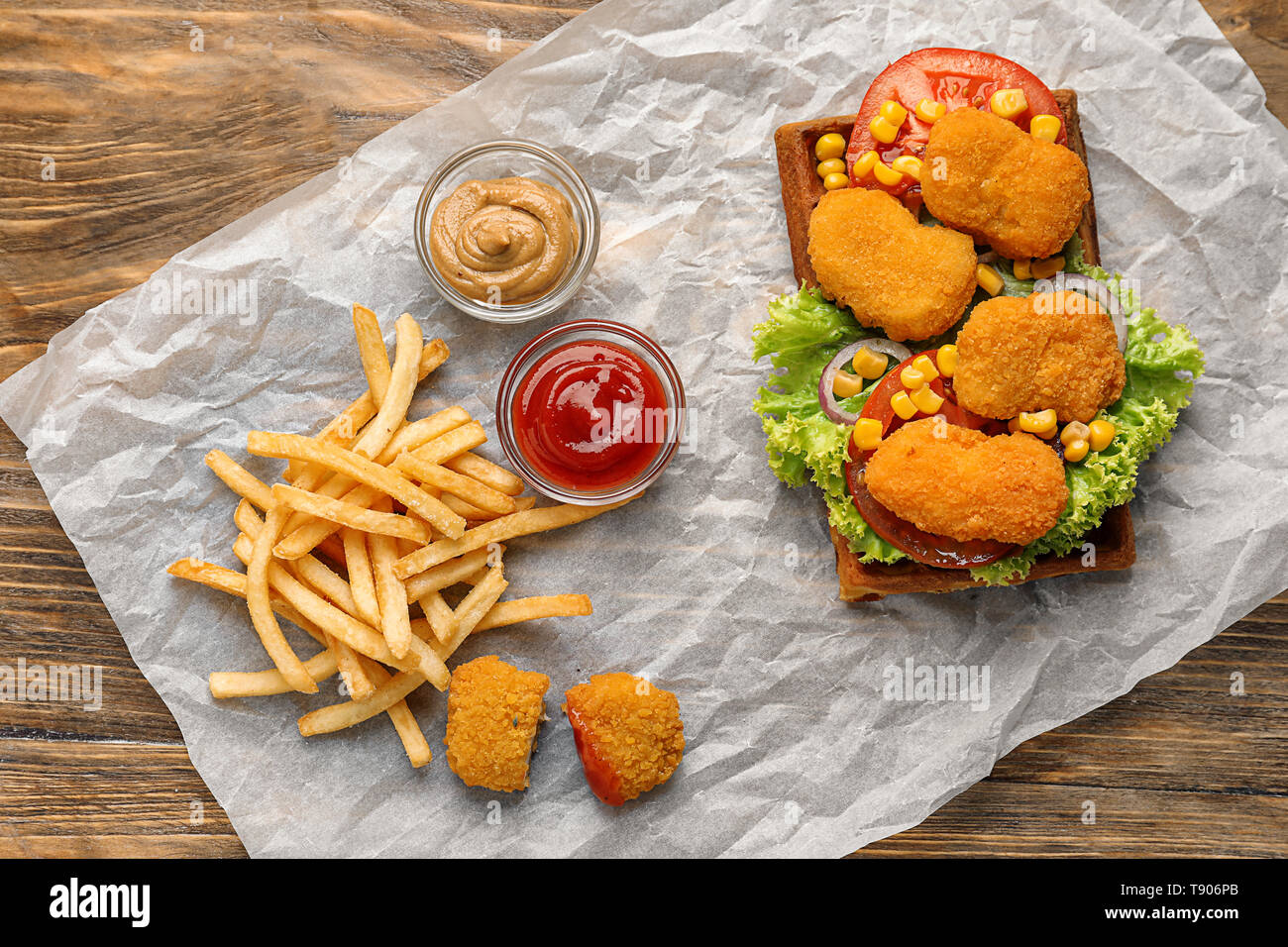 Deliziosa cialda con pepite di pollo e patatine fritte su pergamena Foto Stock