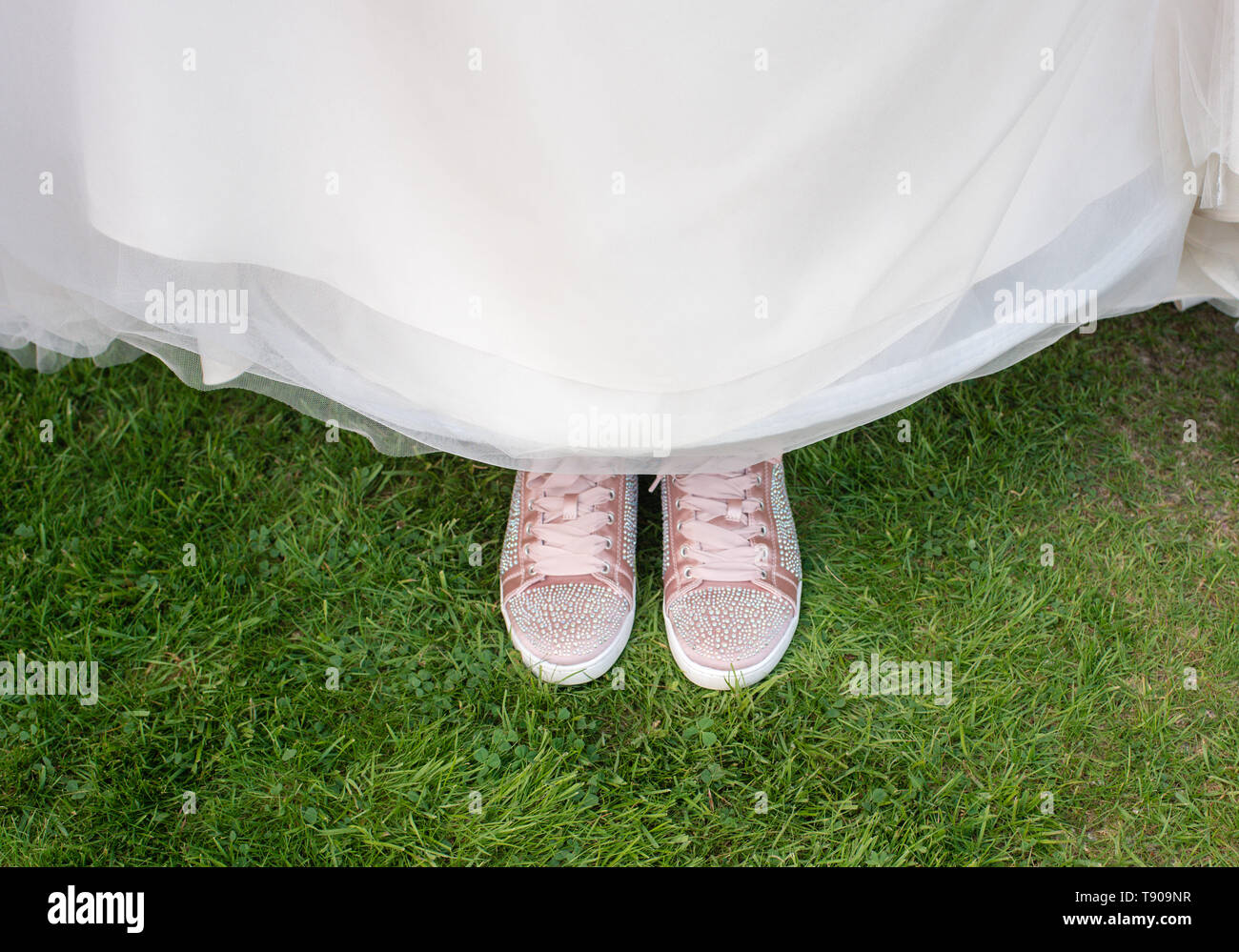 brides indossa scarpe da ginnastica sotto un abito da sposa Foto Stock