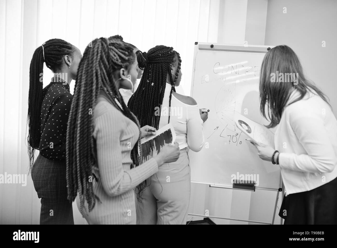 Multirazziale colleghe, equipaggio di divercity partner femminile in office in piedi vicino a lavagna a fogli mobili. Foto Stock