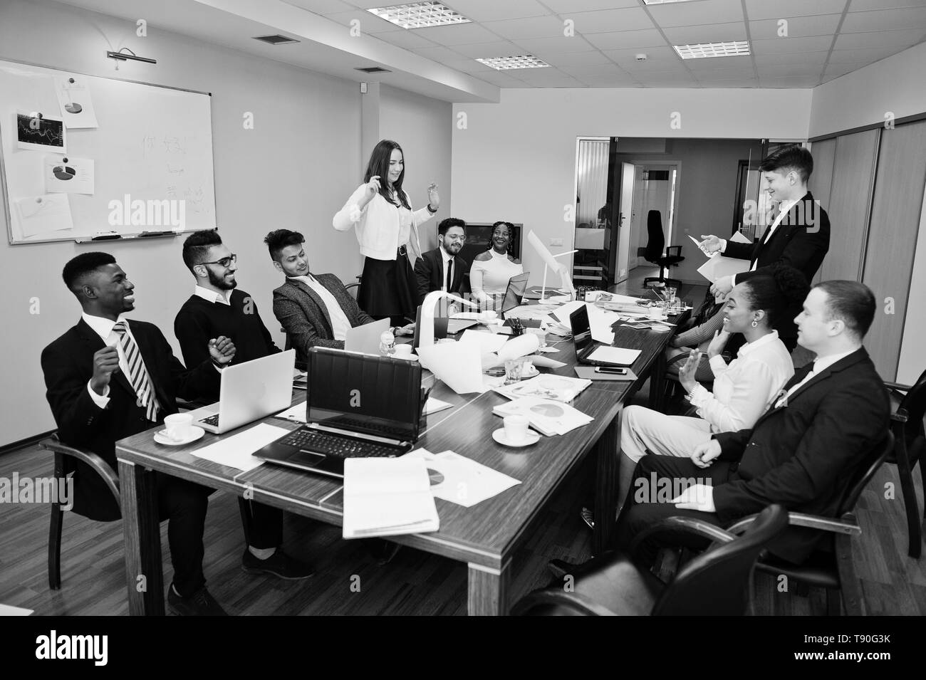 Multirazziale riunioni di team aziendali intorno al tavolo della sala riunioni, due team leader gettare la carta verso l'alto. Foto Stock