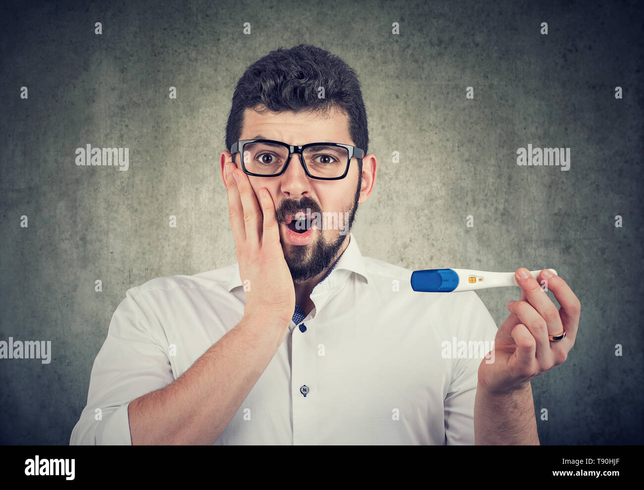 Scioccato l uomo in possesso di una paternità positivo o al test di gravidanza sentimento ansioso Foto Stock