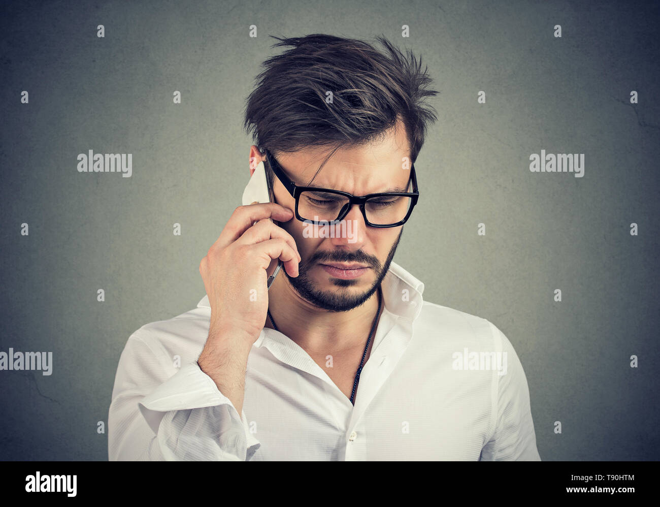 Uomo d affari con espressione triste parlando al telefono mobile guardando verso il basso Foto Stock