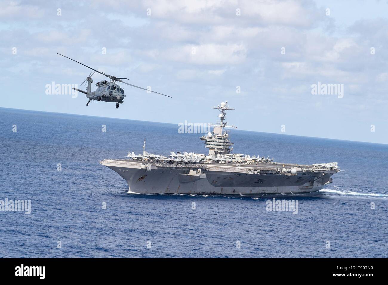 Un U.S. Navy MH-60S Sea Hawk elicottero vola a fianco della Nimitz-class portaerei USS John C. Stennis durante la pattuglia di routine Maggio 9, 2019 in corso nell'Oceano Atlantico. Foto Stock