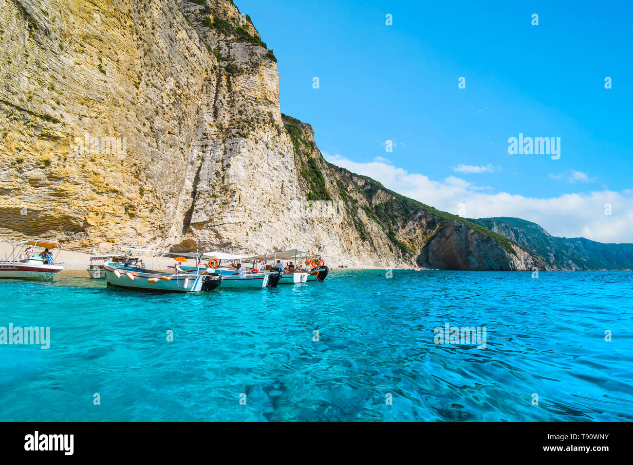 Barche di linea fino al litorale nelle limpide acque fuori dalla sabbiosa spiaggia Paradiso o Chomi Beach in una giornata di sole a Corfu Grecia. Foto Stock