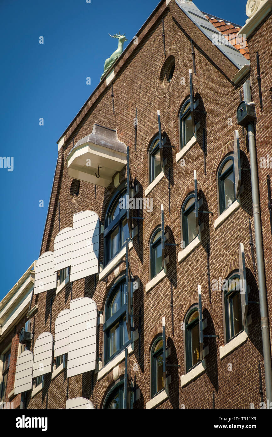 Facciata di un magazzino di Amsterdam con ante aperte del paranco fascio e feste di addio al celibato scultura. Foto Stock