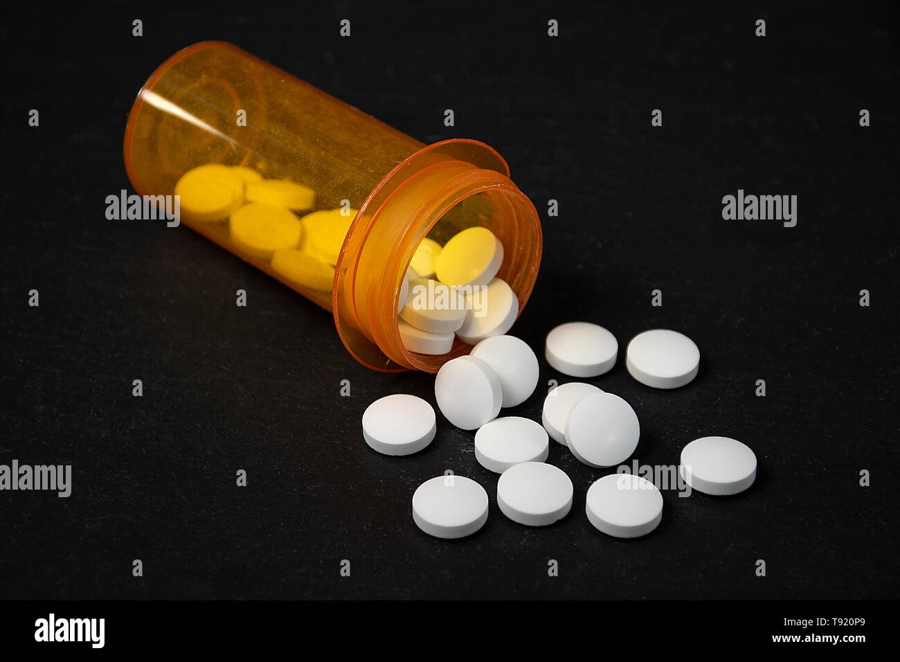 Pillole di bianco fuoriuscita di prescrizione arancione bottiglia su nero Foto Stock