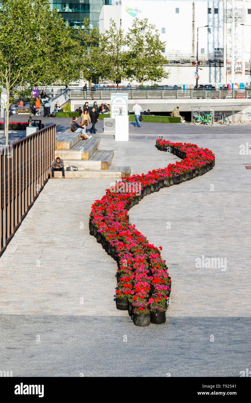 Un nastro di avvolgimento del rosso dei gerani nel recentemente completato il carbone scende cantiere, granaio Square in background, King's Cross, Londra, Regno Unito, 2019 Foto Stock