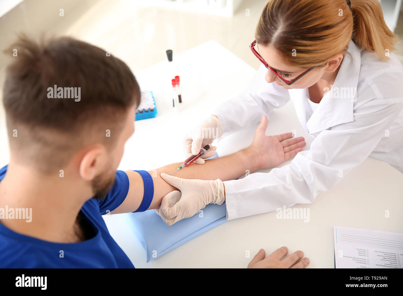 Medico donna prelievo di un campione di sangue del paziente di sesso maschile in clinica Foto Stock