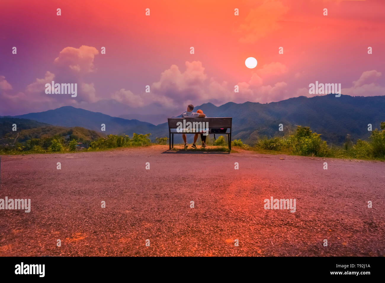 Un paio di lavori di posa in opera su un banco che si affaccia sul fantastico tramonto Begnas Nepal Foto Stock