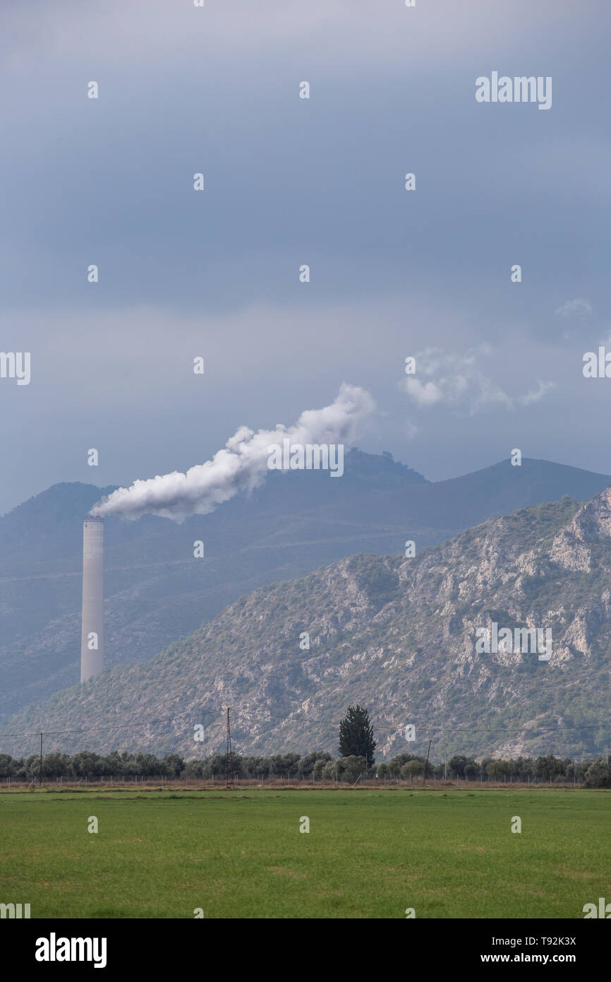 Inquinamento ambientale. Bianco vapore proviene dalla tubazione. Industria fabbrica sul campo. Il paesaggio sullo sfondo verde. Foto Stock