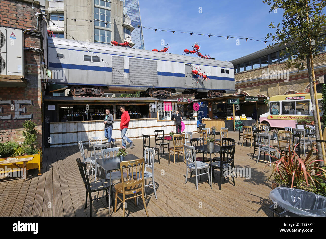 Cantiere di aceto, una nuova area di pop-up bar, caffetterie e bancarelle del mercato vicino alla stazione London Bridge, Londra, Regno Unito. Treno e giant ant artwork da Joe Rush. Foto Stock