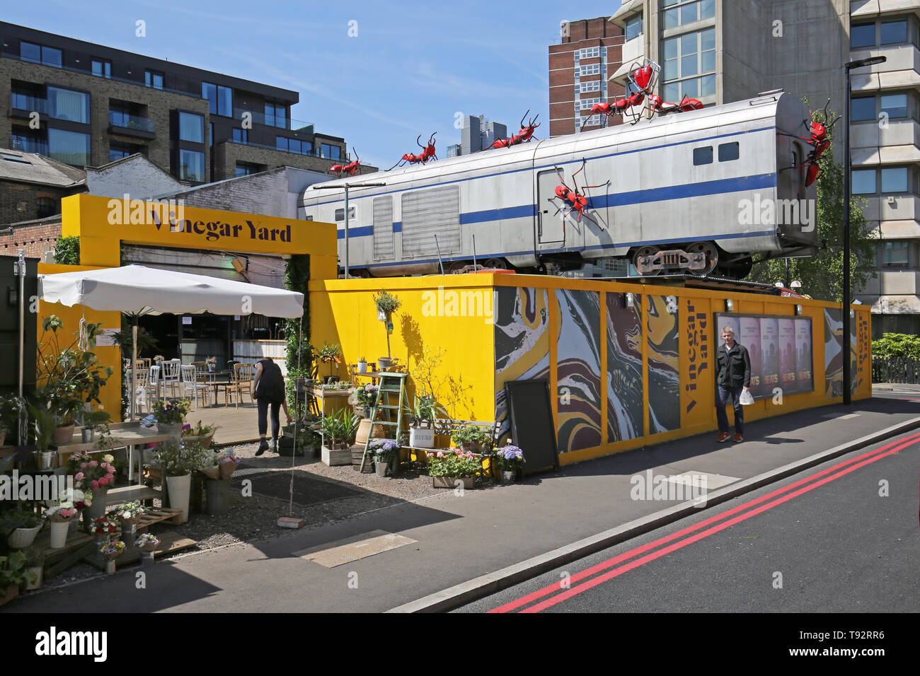 Cantiere di aceto, una nuova area di pop-up bar, caffetterie e bancarelle del mercato vicino alla stazione London Bridge, Londra, Regno Unito. Treno e giant ant artwork da Joe Rush. Foto Stock