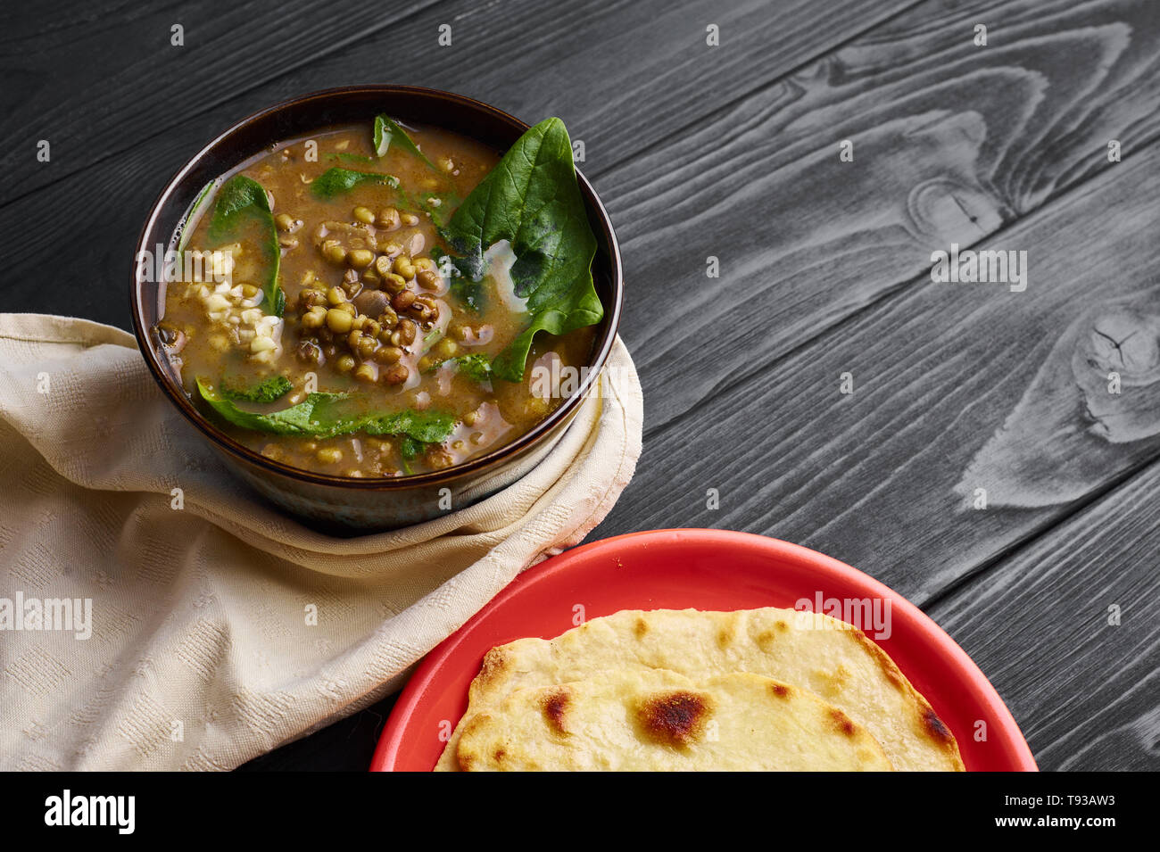 Mung Dhal con spinaci verde al nero da tavolo in legno. Moong Dal - Cucina Indiana curry. Piatto vegetariano con chapati. Spazio di copia Foto Stock