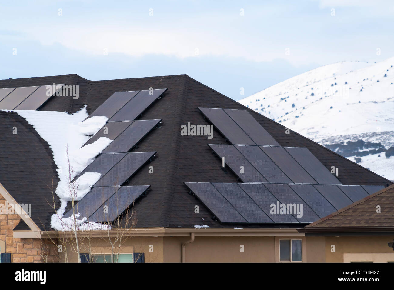 Pannelli solari installati sul tetto scuro di una casa con la neve in inverno Foto Stock