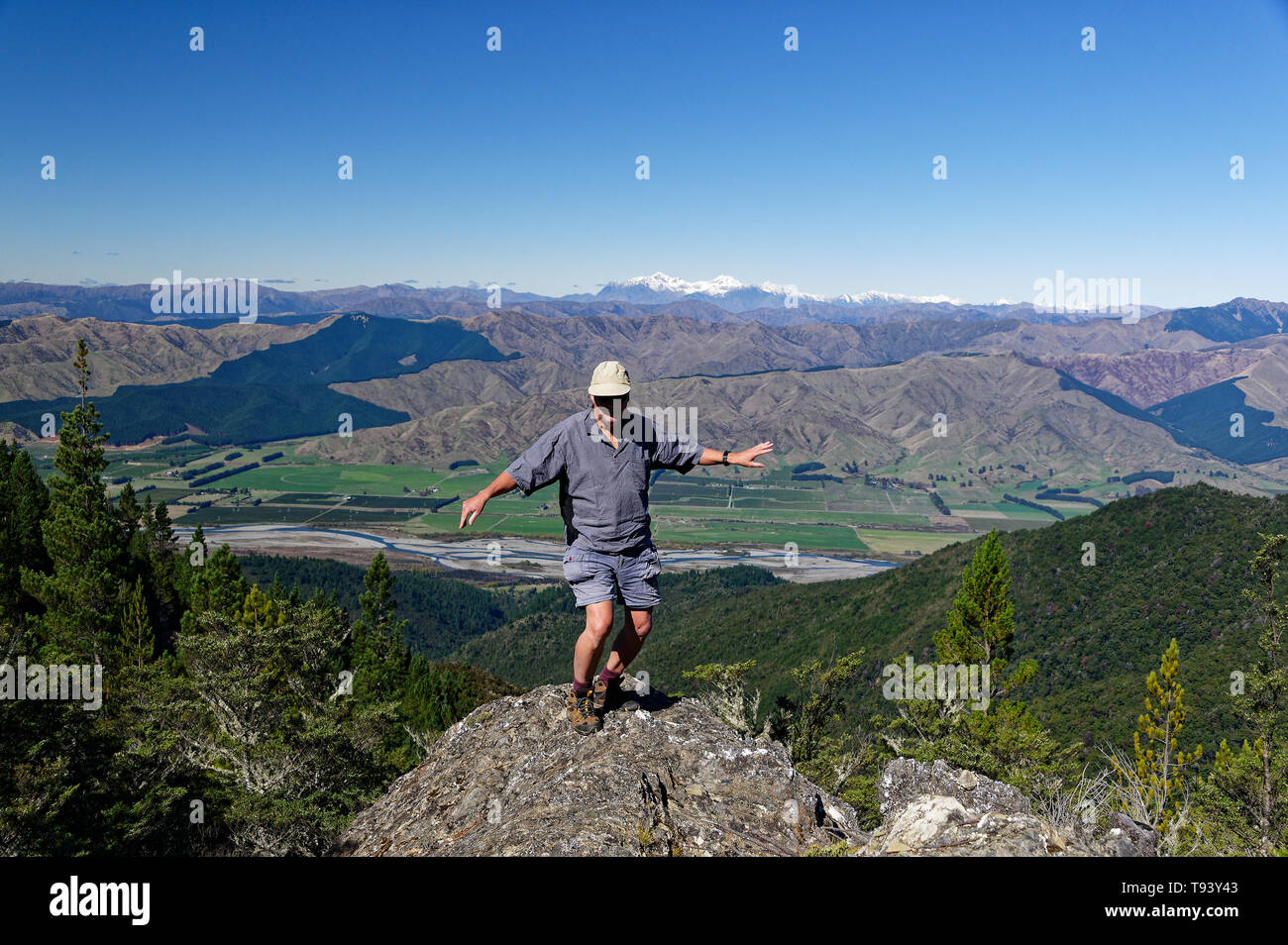 Un uomo gode di una maschera sulla cima di un promontorio roccioso con valle e la montagna dietro Foto Stock