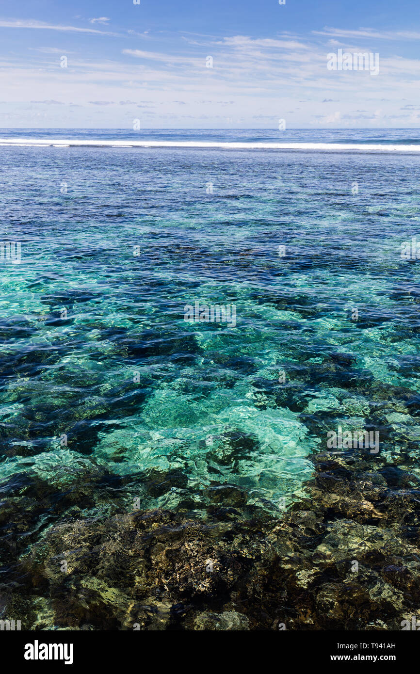 Il chiaro blu oceano pacifico acqua nera con pietre vulcaniche nella barriera corallina su un isola tropicale, Samoa, Polinesia. Foto Stock