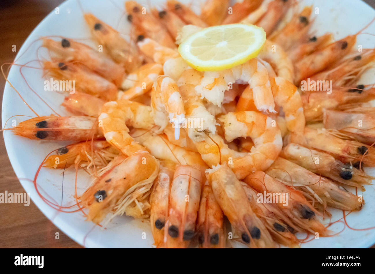 Fritti freschi gamberoni con spicchi di limone su una piastra Foto Stock