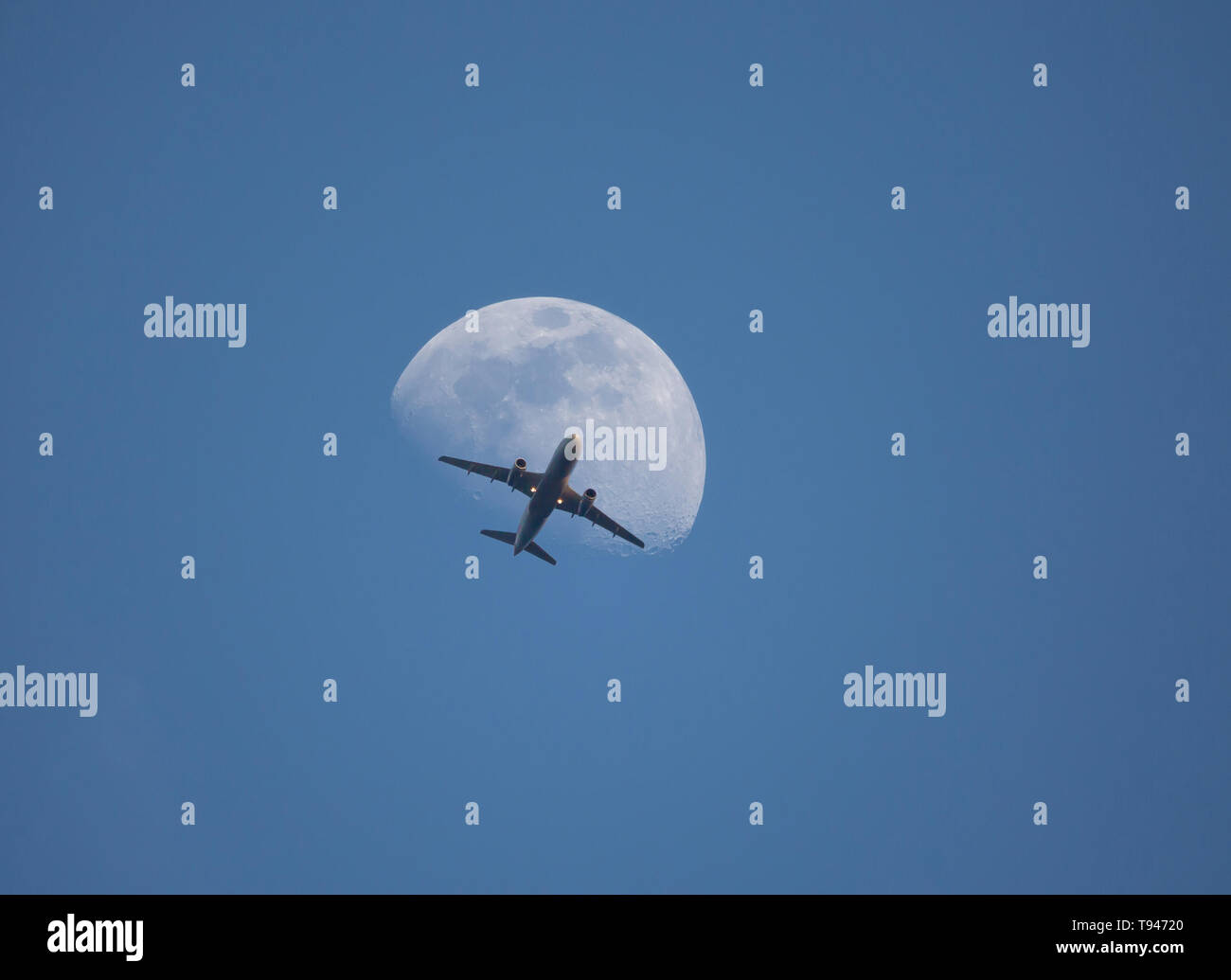 Un aereo commerciale passa davanti alla luna al crepuscolo e poco dopo il decollo. Foto Stock