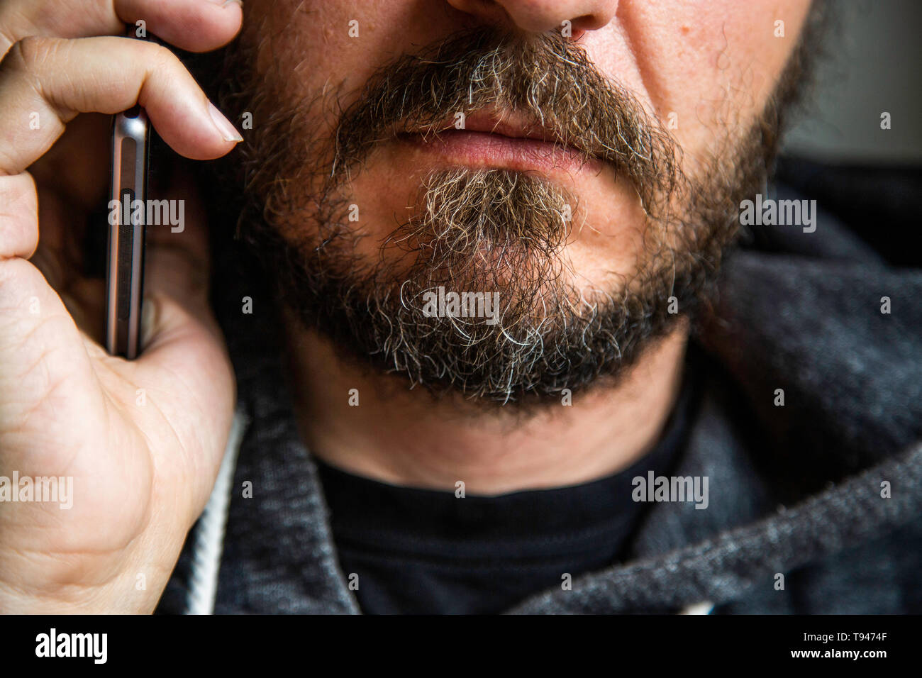 Close up ritratto di uomo barbuto parlando su smart phone, concentrarsi sulle labbra, senza occhi, Segreto parla, penale minaccioso qualcuno Foto Stock