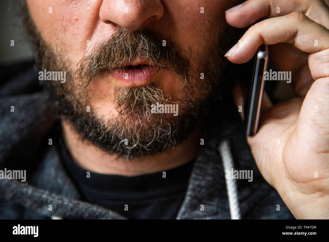 Close up ritratto di uomo barbuto parlando su smart phone, concentrarsi sulle labbra, senza occhi, Segreto parla, penale minaccioso qualcuno Foto Stock