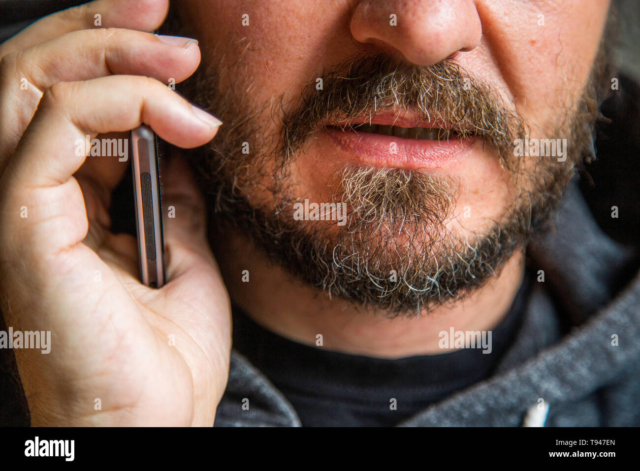 Close up ritratto di uomo barbuto parlando su smart phone, concentrarsi sulle labbra, senza occhi, Segreto parla, penale minaccioso qualcuno Foto Stock