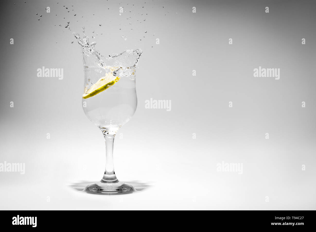 Un drink di soda splash fotografato come una fetta di limone cade nel vetro. Foto Stock