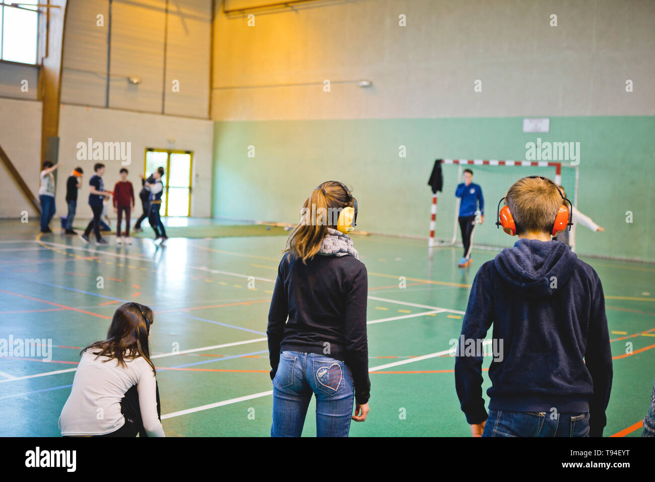 Disability Awareness in ambiente scolastico. I giovani allievi della scuola secondaria la pratica di uno sport con cuffie per capire in che modo è di essere sordi Foto Stock
