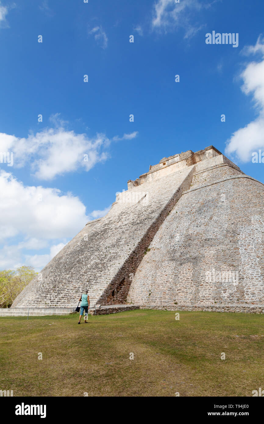 La piramide Maya - turista alla ricerca fino a piramide del mago, viaggi e turismo; presso le rovine maya di al sito UNESCO di Uxmal, Messico America Latina Foto Stock