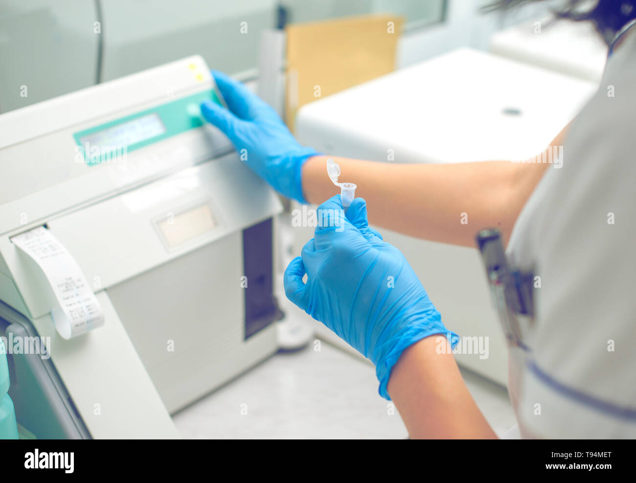 La donna lavora in un laboratorio su una moderna macchina per prove del sangue. Medico controlla il sangue dei pazienti. La ricerca di sangue in un moderno wo scientifica Foto Stock