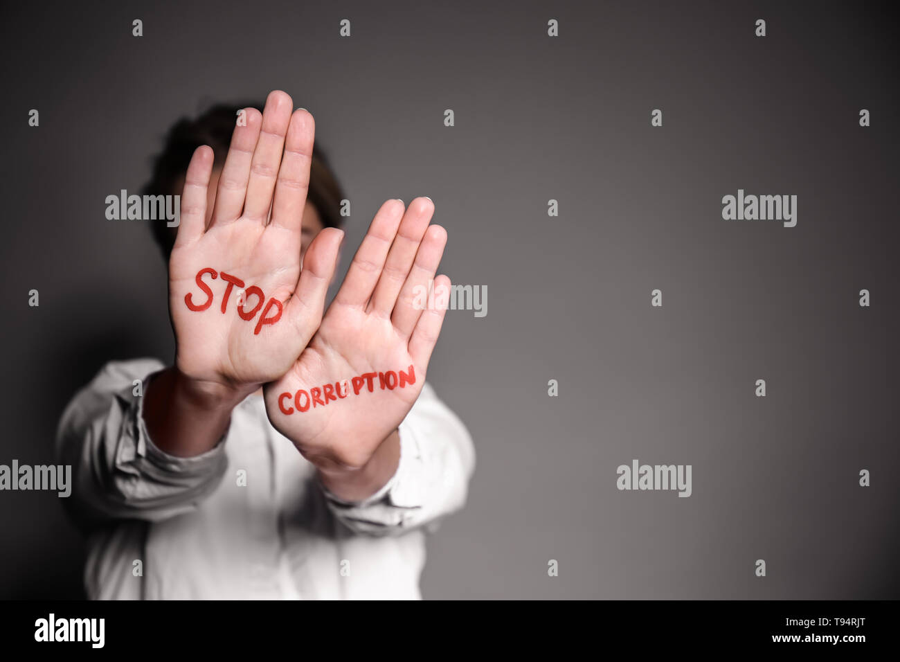 Donna con testo STOP ALLA CORRUZIONE scritto sui suoi palmi delle mani contro lo sfondo grigio Foto Stock