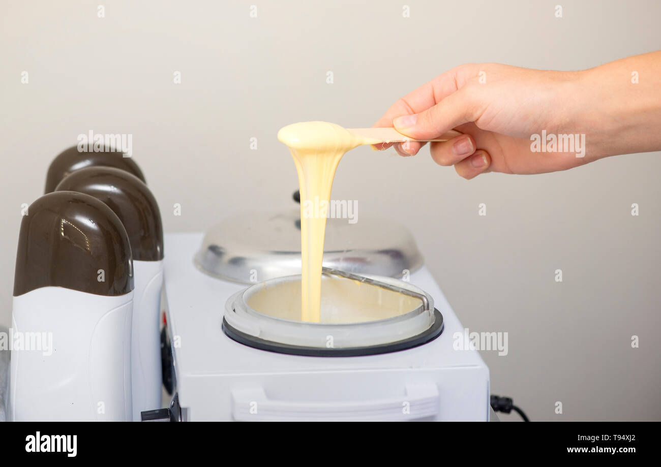 Donna preparando la cera per la depilazione Foto Stock