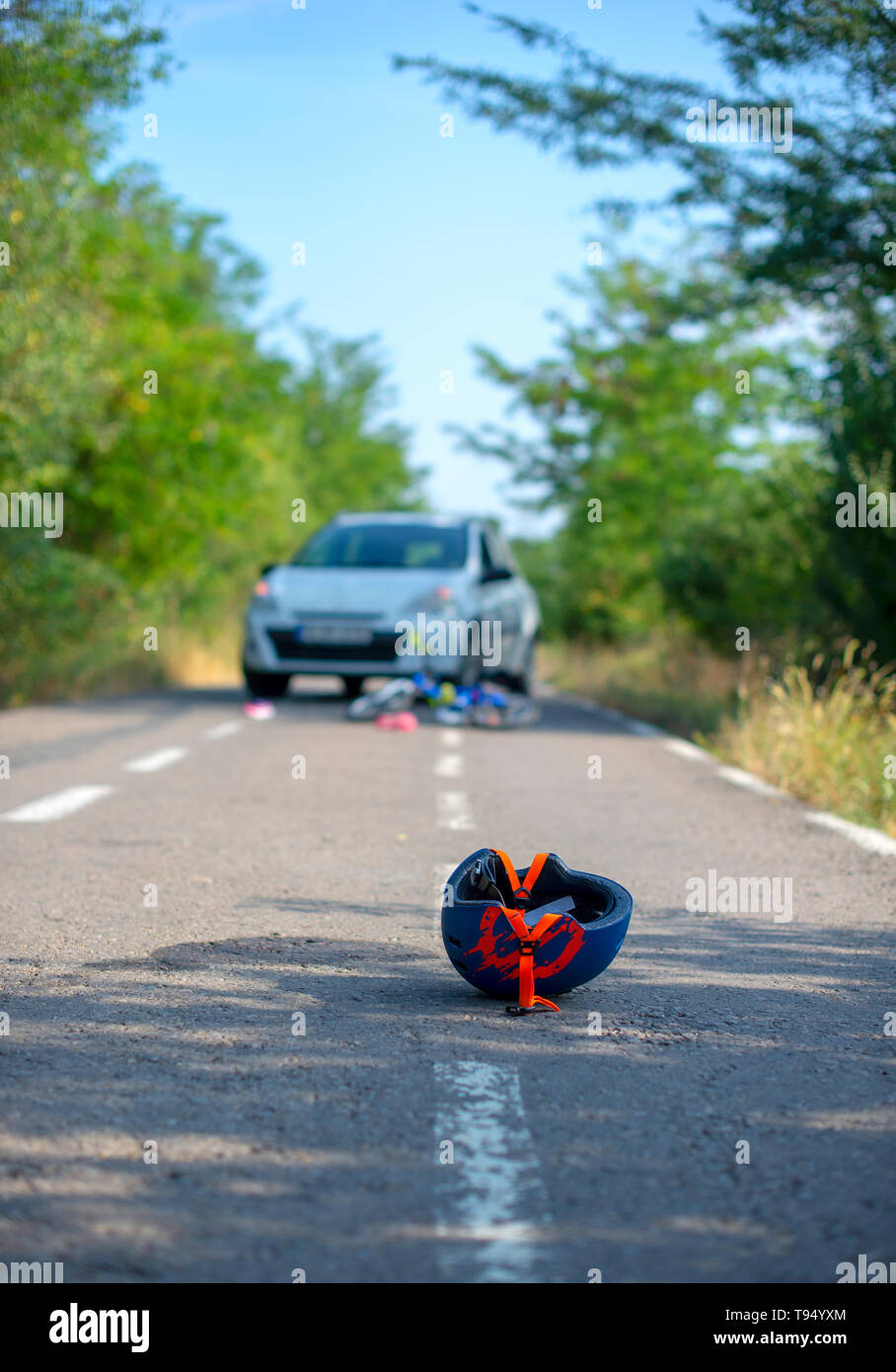 Close-up di un ciclismo casco caduto su asfalto accanto a una bicicletta dopo l incidente di auto sulla strada Foto Stock