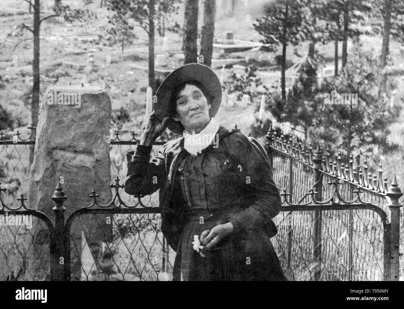 Calamity Jane, in piedi presso la tomba di Wild Bill Hickok, photogrpahed di J.A. Kumpf, 1903. Martha Jane Canary (1 maggio 1852 - 1 agosto 1903), meglio noto come Calamity Jane, era un American frontierswoman e professional scout. Ella ha ricevuto poca o nessuna istruzione formale ed era analfabeta. Ha lavorato come una lavastoviglie, un cuoco, una cameriera, una sala da ballo girl, un infermiere e un bue team driver. Nel 1874, ha trovato lavoro come uno scout a Fort Russell. Foto Stock