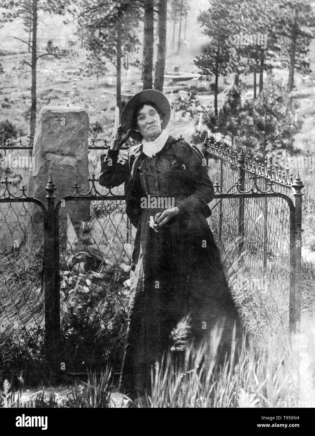 Calamity Jane, in piedi presso la tomba di Wild Bill Hickok, photogrpahed di J.A. Kumpf, 1903. Martha Jane Canary (1 maggio 1852 - 1 agosto 1903), meglio noto come Calamity Jane, era un American frontierswoman e professional scout. Ella ha ricevuto poca o nessuna istruzione formale ed era analfabeta. Ha lavorato come una lavastoviglie, un cuoco, una cameriera, una sala da ballo girl, un infermiere e un bue team driver. Nel 1874, ha trovato lavoro come uno scout a Fort Russell. Foto Stock