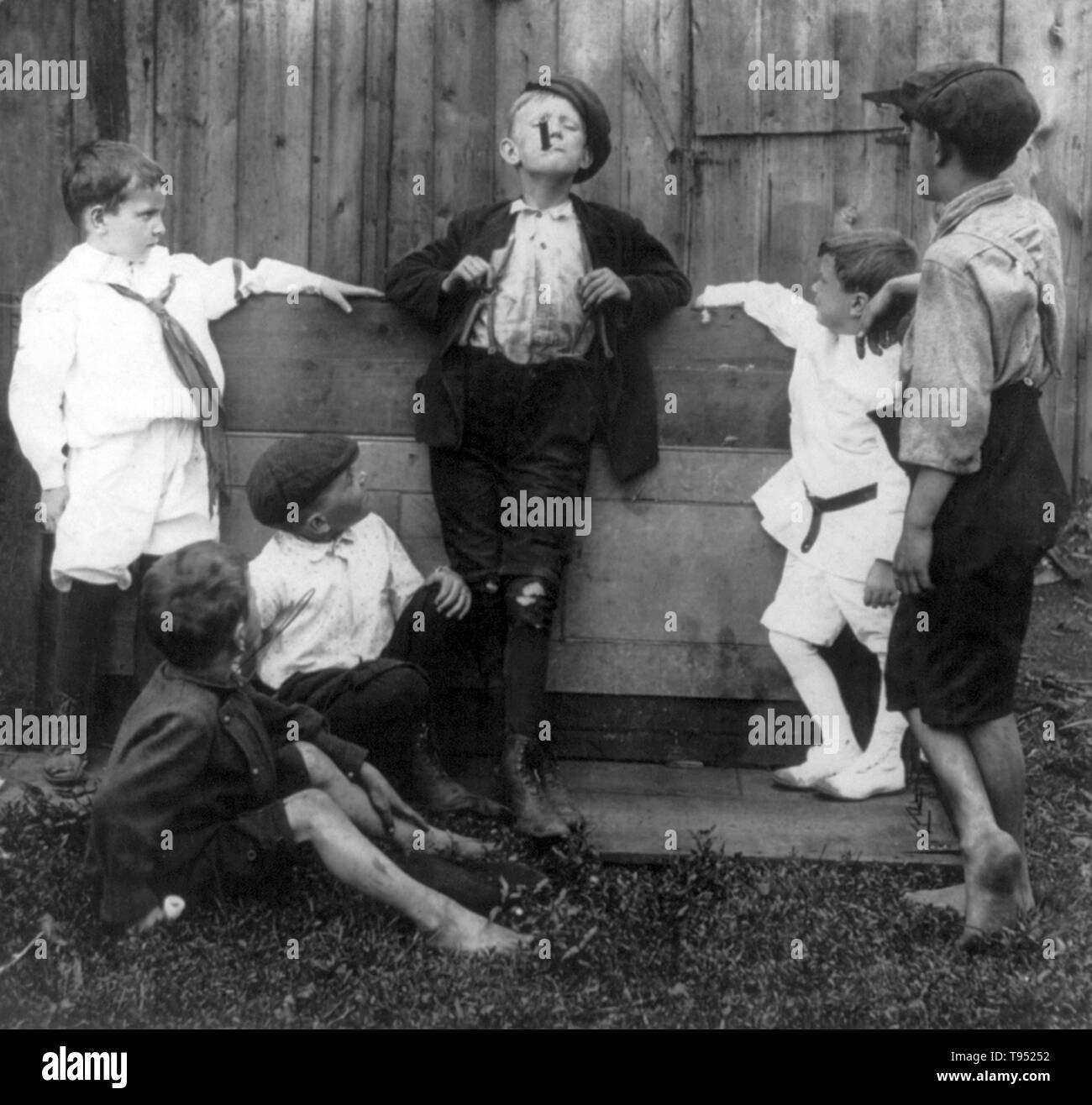 Titolo: "L'insegnante" mostra cinque ragazzi guardando un altro fumare un sigaro. Stereografia ritagliata fotografata da E.W. Kelley, 1906. Foto Stock