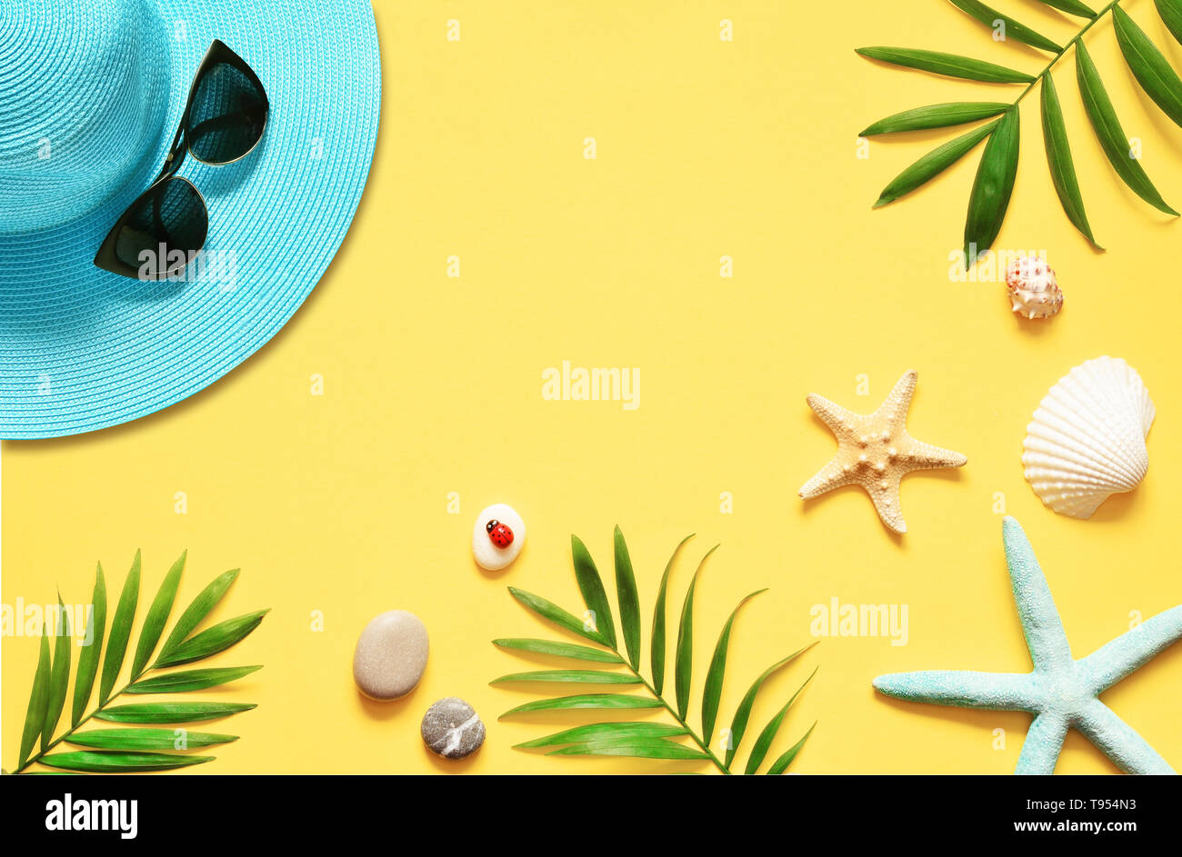 Sfondo tropicale. Palme rami, hat con stella marina e conchiglia su sfondo giallo. Il viaggio. Spazio di copia Foto Stock