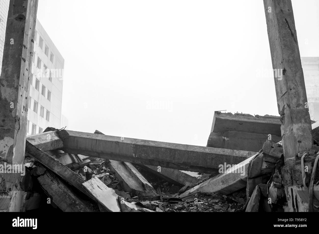 Distrutto il grande edificio in cemento in una nebbiosa opacità. I resti del telaio grigio di pali in calcestruzzo ed i detriti della struttura dell'edificio. Sfondo. Foto Stock