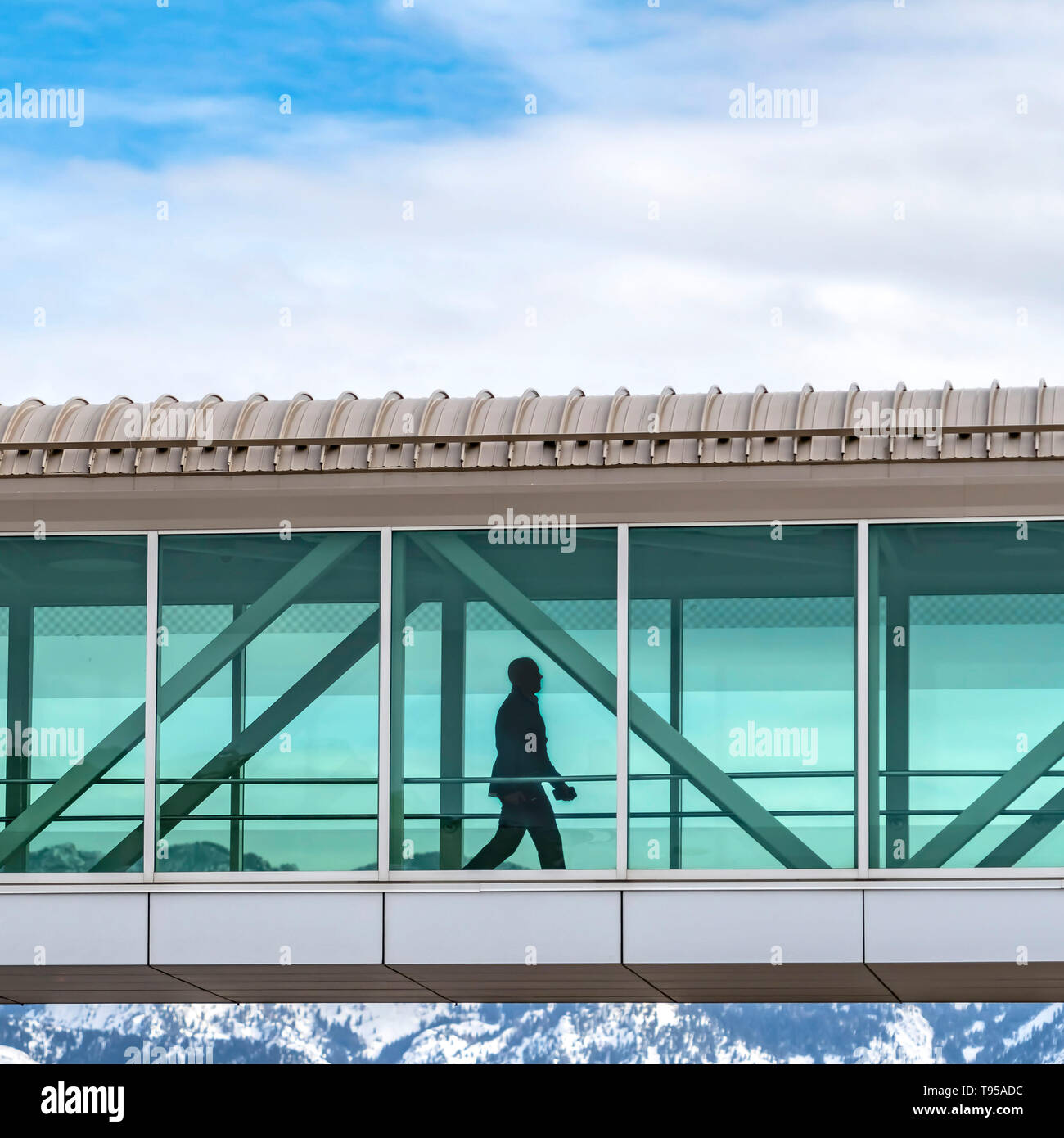 Square Silhouette di un uomo a piedi all'interno di un ponte sopraelevato che collegano gli edifici Foto Stock