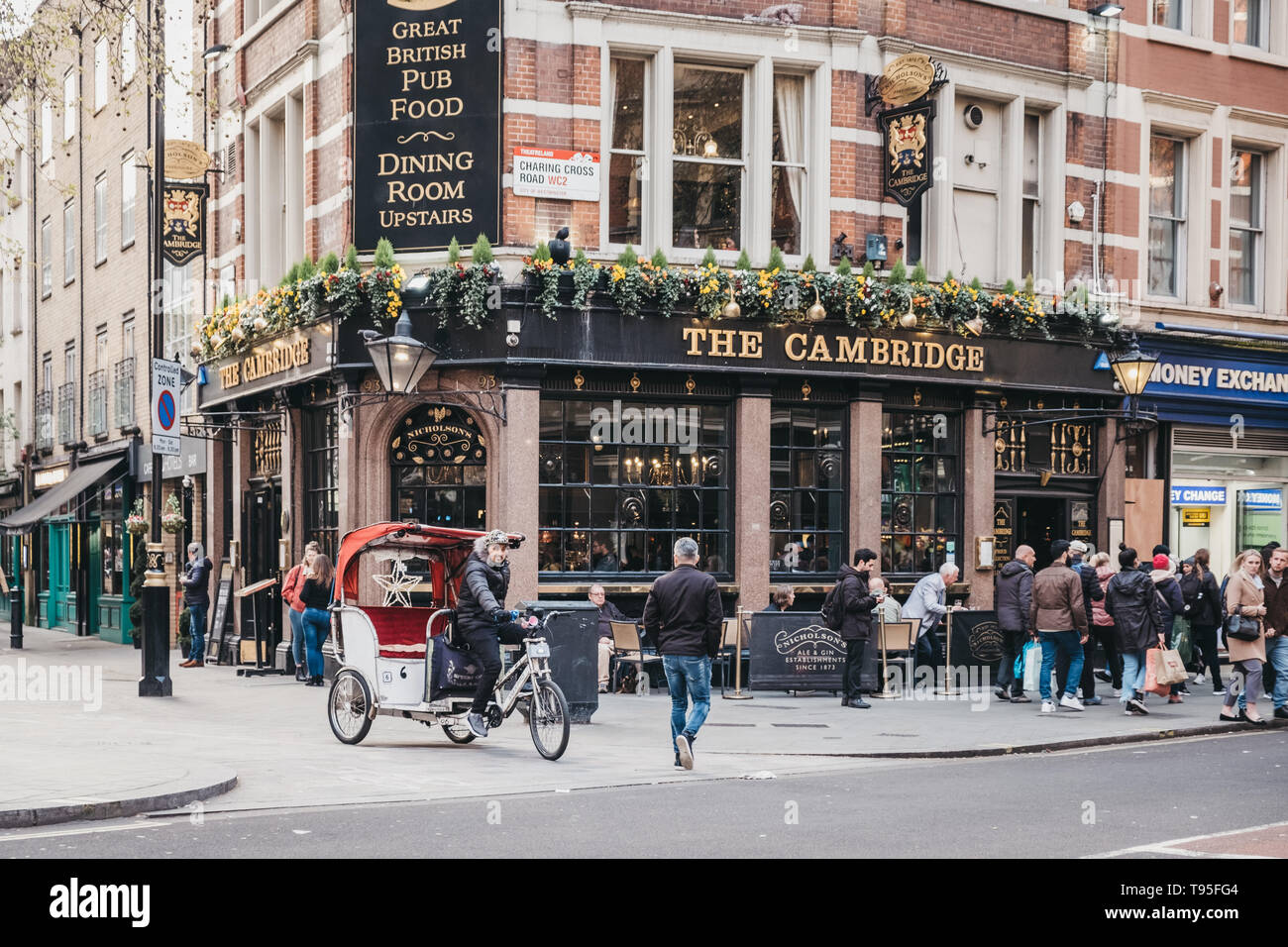 London, Regno Unito - 13 Aprile 2019: Rickshaw su una strada di fronte al Cambridge, un tradizionale pub di carattere unico accanto al Palazzo del Teatro su Chari Foto Stock