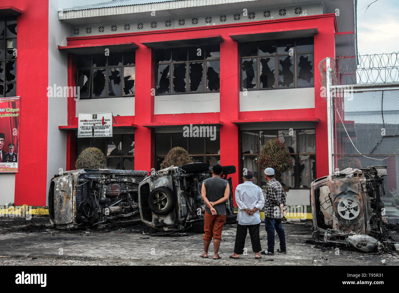 Il nord di Sumatra, Indonesia. 16 Maggio, 2019. La gente guarda i veicoli bruciati nella parte anteriore del Langkat prigione a seguito di una sommossa nel nord di Sumatra, Indonesia, il 16 maggio 2019. Centinaia di detenuti in carcere per tossicodipendenti detenuti nella provincia del Nord Sumatra la reggenza di Langkat riuscì a sfuggire il giovedì a seguito di una sommossa incitato da un conflitto tra operai e i detenuti. Credito: Alberth Damanik/Xinhua/Alamy Live News Foto Stock