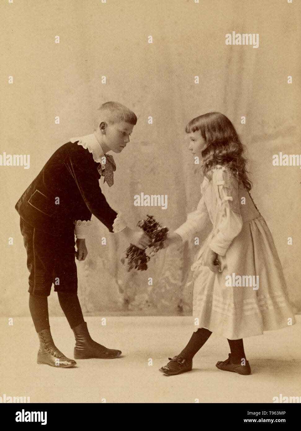 Ragazzo giovane si inchinano e presentando un mazzo di fiori per un curtseying giovane ragazza. George H. Hastings, fotografo (American, circa 1849 - 1931). Albume silver stampa, 1880. Foto Stock