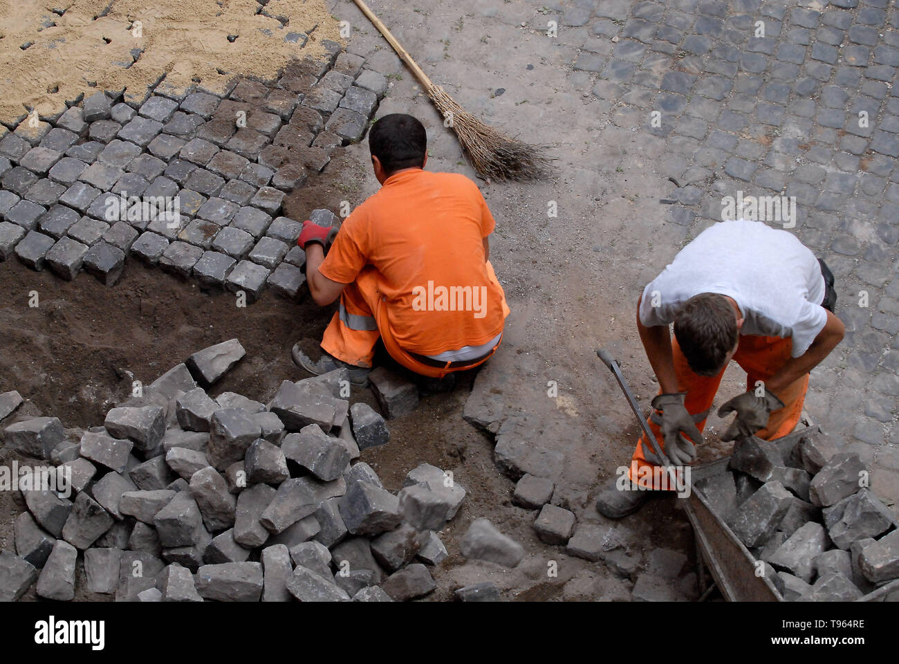 Roma, via Merulana. Italia: lavoratori sanpietrino pavimentazione pietre. Foto Stock