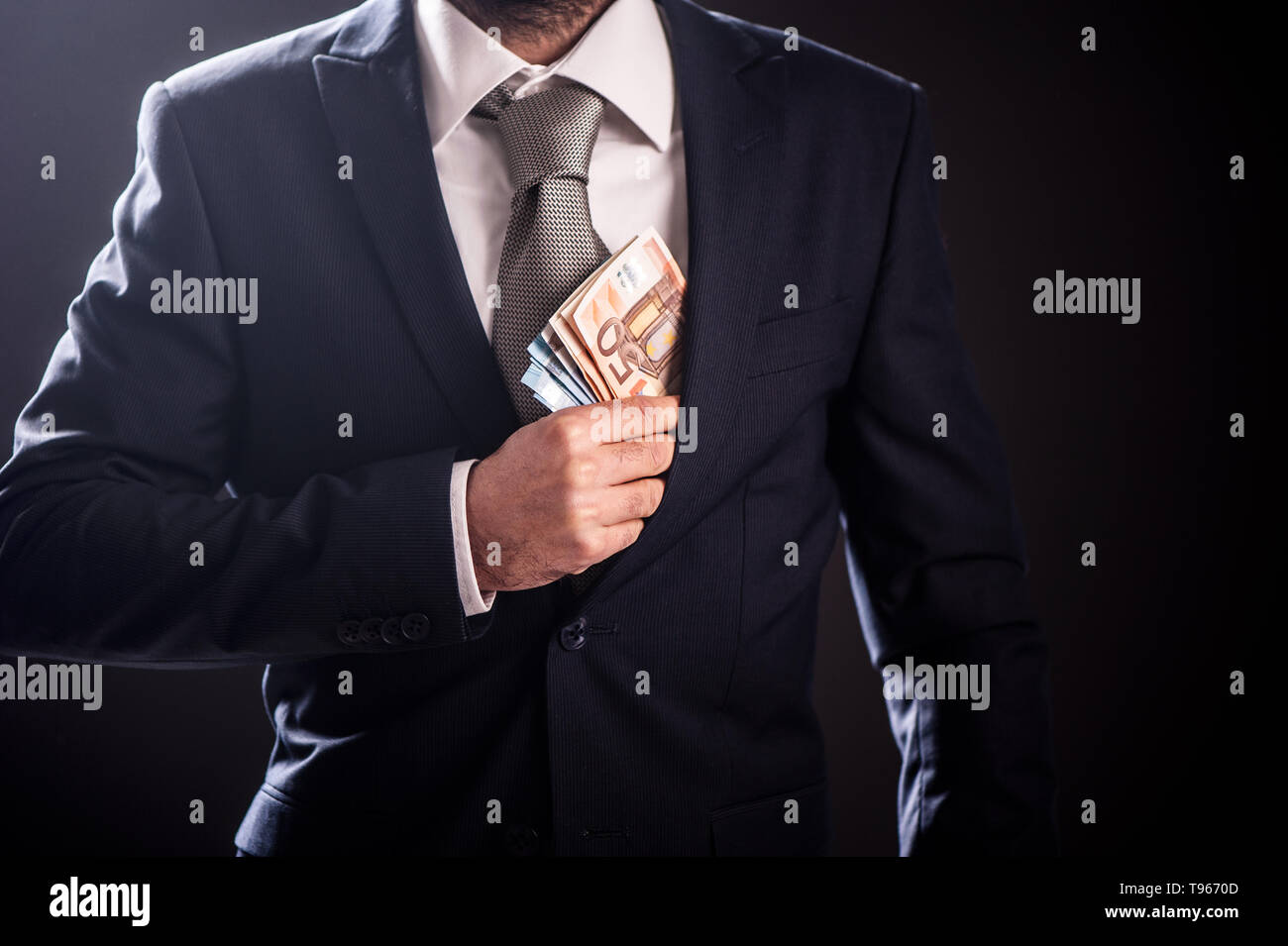 Imprenditore mettendo il denaro in tasca, uomo elegante suite e legare con le banconote in euro da vicino Foto Stock