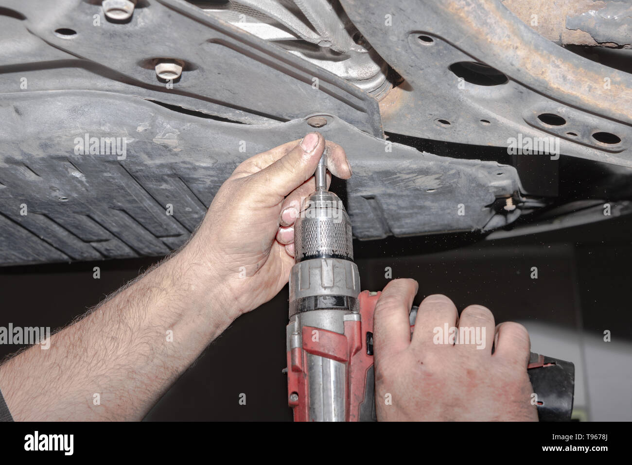 Meccanico al lavoro. Fissare la vite con il cacciavite a batteria Foto Stock