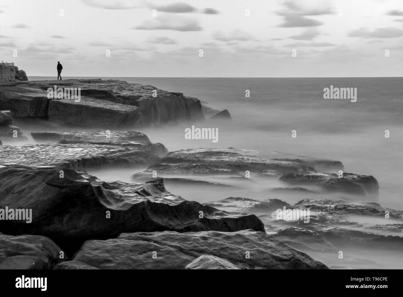 Lone uomo sulla roccia misty ocean shore Foto Stock